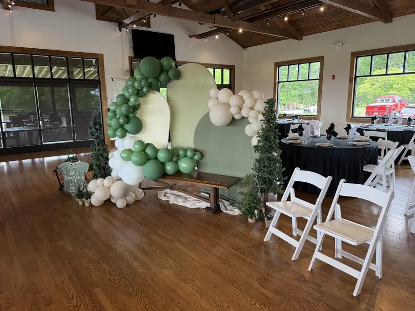 Sage and cream balloon arch backdrop set up in the banquet room for a baby shower
