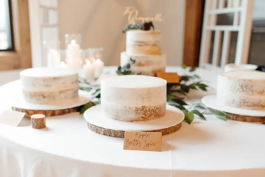 Naked wedding cakes with greenery and candles on a cake table